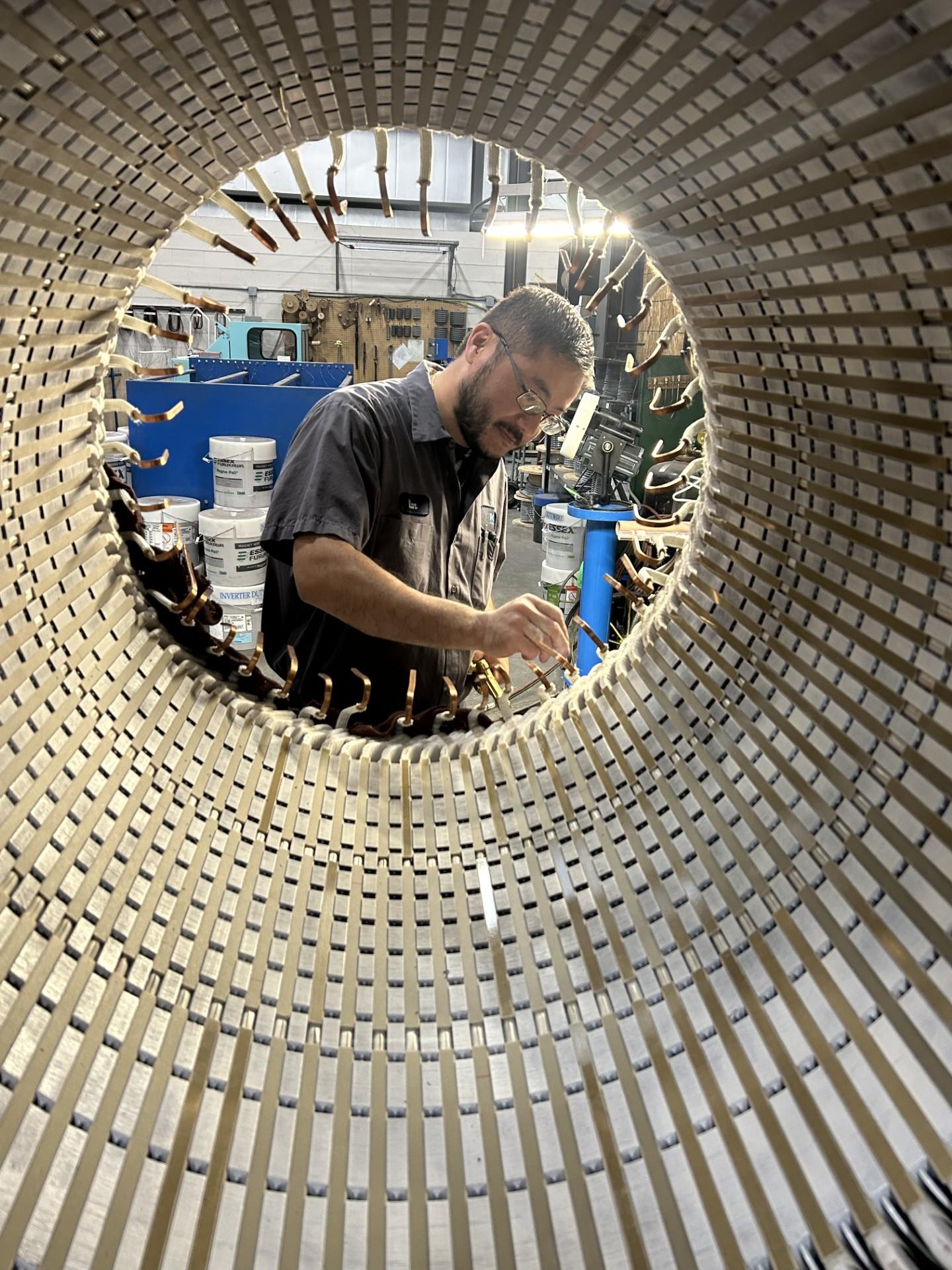 Technician working inside electric motor stator with precision tools